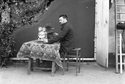 Dans cette photographie, Léon Bollée utilise un modèle de sa machine à calculer inventée en 1889. Il est assis à une table devant une porte-fenêtre de la maison au 81 bis avenue de Paris..jpg